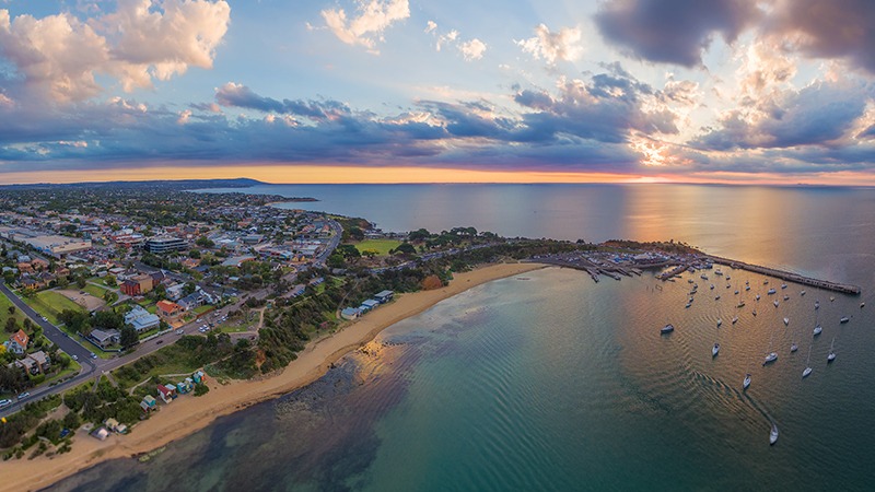 Scenic coastal road along the Mornington Peninsula coastline with ocean views and colourful sunset skies